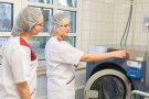 Zwei junge Frauen stehen an einer industriellen Waschmaschine