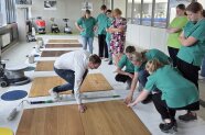Studierende des 3. Schuljahres lassen sich verschiedene Holzböden und deren Pflege erklären