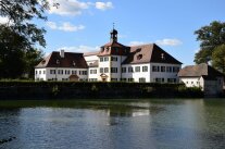 Weißes Schloss der Fachakademie vor einem Teich
