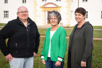 3 Personen stehen nebeneinander im Freien