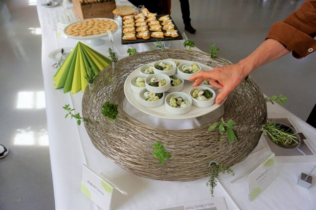 Rucola-Pesto und Kräuterbutter in kleinen Schüsseln auf einem Buffet angerichtet.